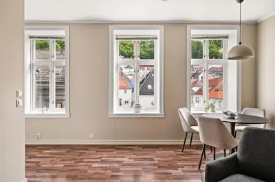 a living room with a table and chairs and windows at BB Apartments I 300m to Bryggen & Train Station in Bergen