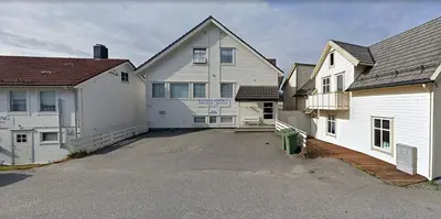 a large white house with a driveway next to two buildings at Seljevaagen Penthouse in Selje