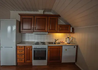 a kitchen with wooden cabinets and a white refrigerator at Seljevaagen Penthouse in Selje