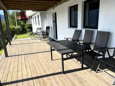 a wooden deck with chairs and a picnic table at Fjord view apartment in Vaksdal