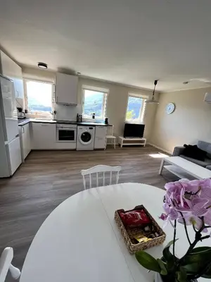 a kitchen and living room with a white table at Fjord view apartment in Vaksdal