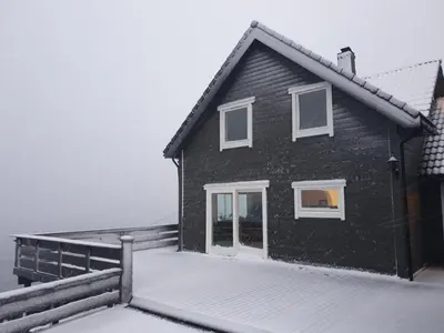 a black house with white windows and snow on the ground at Bluewater Cottage - Blåvannshytta in Bergen