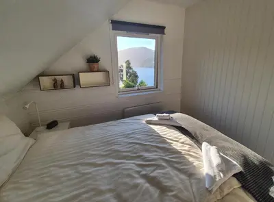 a bedroom with a bed with a window at Bluewater Cottage - Blåvannshytta in Bergen