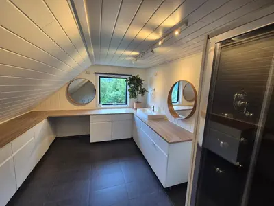 an attic bathroom with a sink and two mirrors at Bluewater Cottage - Blåvannshytta in Bergen
