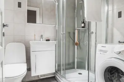a bathroom with a shower and a washing machine at Cozy apartment at Laksevåg! in Bergen