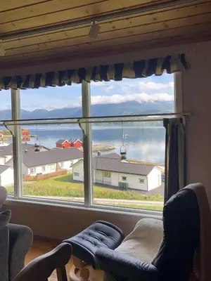 a living room with a large window with a view of a house at Stall Rygg Apartment, Gloppen