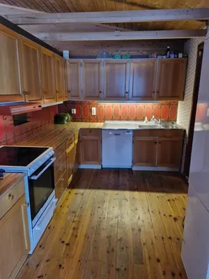 a kitchen with wooden cabinets and a wooden floor at Stall Rygg Apartment, Gloppen