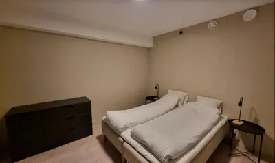 a bedroom with a bed with white sheets and a dresser at Central and Spacious Apartment for 6 in Trondheim