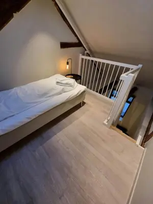 a small bedroom with a bed and a staircase at Central and Spacious Apartment for 8 in Trondheim