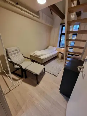 a room with a bed and a chair and a staircase at Central and Spacious Apartment for 8 in Trondheim
