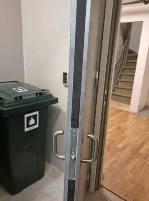 a door leading into a room with a trash can at Central Apartment for 2 in Trondheim