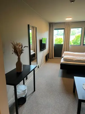 a room with a bed and a table and a mirror at Elvehagen Hotell in Sande