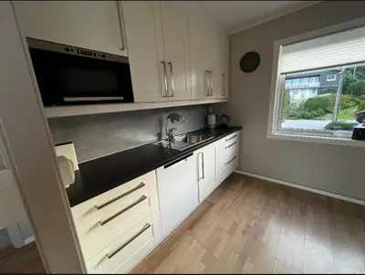 a kitchen with white cabinets and a sink and a window at Koselig leilighet med utsikt, gåavstand fra sentrum in Stord