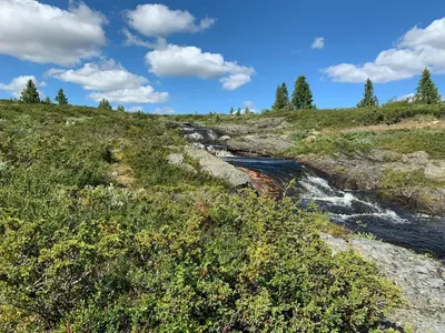 a stream on a grassy hill with a blue sky at Modern Cabin With Views Of Hallingskarvet in Torpo