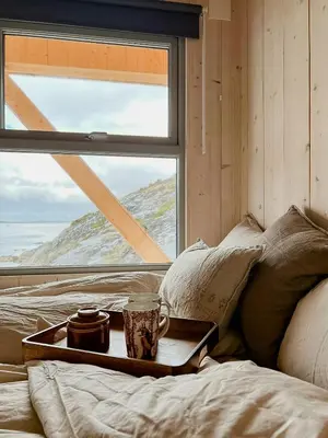 a tray sitting on a bed in front of a window at Architectural Gem On Rocks In Kvenvær in Kvenvær