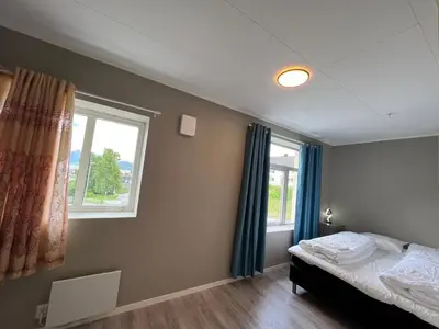 a bedroom with a bed and two windows at Åndalsnes House---Apartments in Åndalsnes