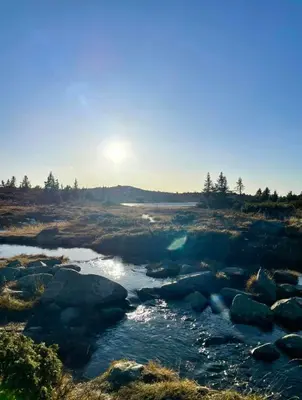 a river with rocks and the sun in the background at Magiske Vinterdage I Sjusjøen in Mesnali