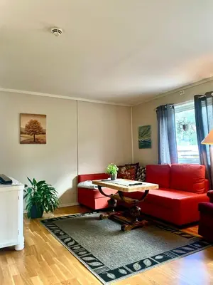 a living room with a red couch and a table at Signegarden in Skjåk