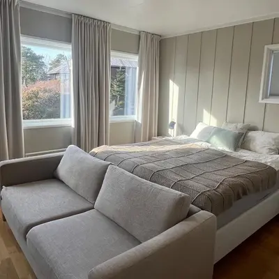 a bedroom with a bed and a couch and a window at Leilighet nær Color Line i Larvik in Lii