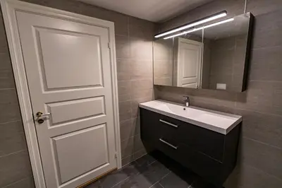 a bathroom with a sink and a mirror and a door at Kozy apartment near Bergen city center with free parking and Wifi in Bergen