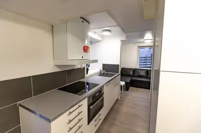 a kitchen with white cabinets and a couch in the background at Kozy apartment near Bergen city center with free parking and Wifi in Bergen