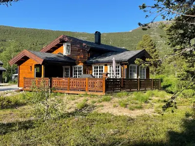 a log home with a large deck on a hill at Sjarmerende tømmerhytte på Bjorli in Lii