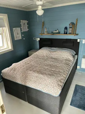 a bedroom with a bed in a blue room at Cabin With Sea Views In Mjømna