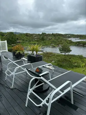 a deck with chairs and a table and a river at Cabin With Sea Views In Mjømna
