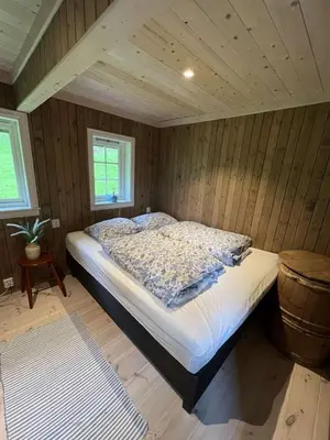a bedroom with a bed in a room with wooden walls at Gamlestova in Viksdalen