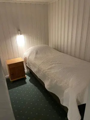a small bedroom with a bed and a night stand at Sokkelleilighet med 3 soverom in Molde