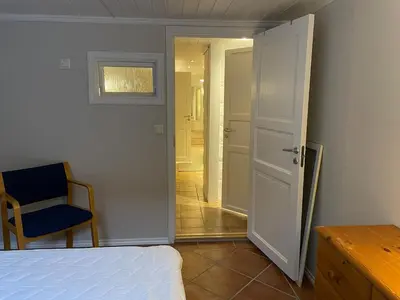 a bedroom with a bed and a chair and a door at Sokkelleilighet med 3 soverom in Molde