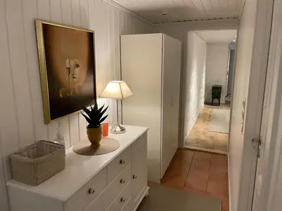 a room with a dresser with a lamp and a hallway at Sokkelleilighet med 3 soverom in Molde