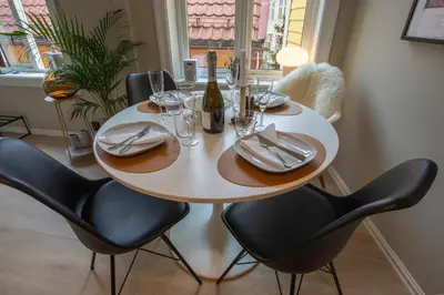 a table with chairs and a bottle of wine at Cosy flat in historical lane in Bergen