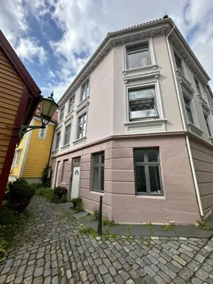 a white and pink house on a cobblestone street at Cosy flat in historical lane in Bergen