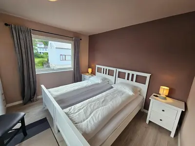 a bedroom with a white bed and a window at Newly renovated apartment in beautiful Haramsøy in Ålesund