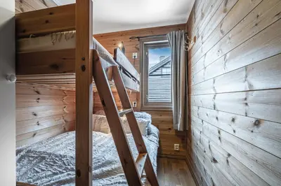 a bedroom with a bunk bed and a wooden wall at Spacious Family Apartment in Hemsedal, Ski In-Out, Sauna, 30m from Skarsnuten hotell in Hemsedal