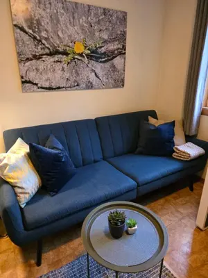 a blue couch in a living room with a table at Rom 3 i bufellesskap in Sogndal
