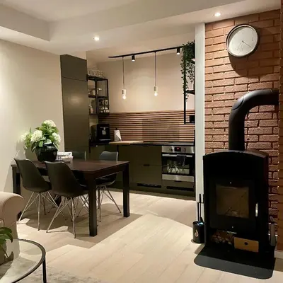 a kitchen and living room with a fireplace and a table at Private room with a view and garden - 12 min from the city center in Bergen
