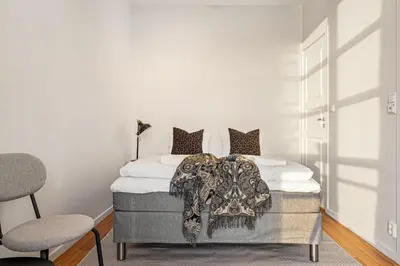 a bedroom with a bed and two chairs at Heimby Homes - Seaside Balcony Stay in Bergen