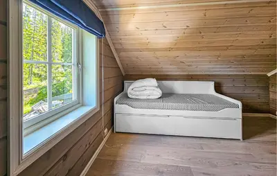 a bed in a wooden room with a window at Awesome Home In Vinje With Sauna in Trovatn