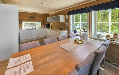 a kitchen and dining room with a wooden table and chairs at Awesome Home In Vinje With Sauna in Trovatn