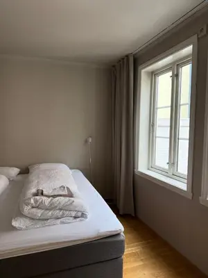 a bed in a room with a window at Romslig leilighet midt i Bergen sentrum - komfort med kvalitetsenger og dyner in Bergen