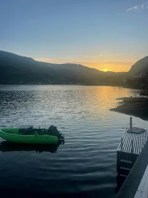 a green boat sitting in the water at a dock at Renovated 1918 House By The Sea In Sandeid in Sandeid