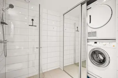 a bathroom with a washing machine and a glass shower at Modern & Spacious City Apartment in Bergen
