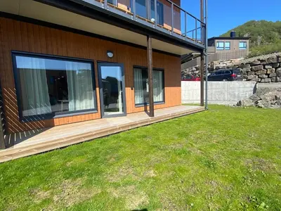 a house with a deck and a grass yard at Modern apartment in beautiful Lofoten in Lii