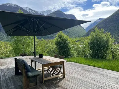 a wooden table with an umbrella on a deck at Historic Cabin By Lærdal River in Tønjum