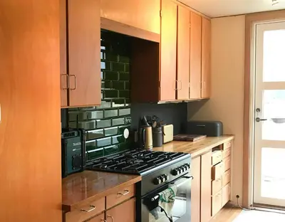 a kitchen with a stove and wooden cabinets at Historic Cabin By Lærdal River in Tønjum
