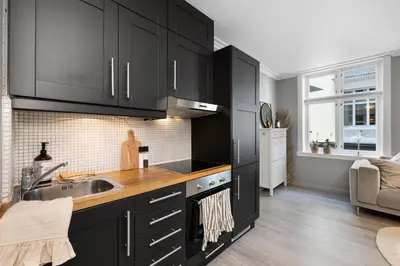 a kitchen with black cabinets and a sink at Charming Apartment, Walk to Everything in Bergen in Lii