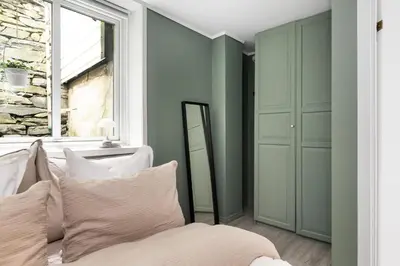 a bedroom with green walls and a bed with white pillows at Charming Apartment, Walk to Everything in Bergen in Lii