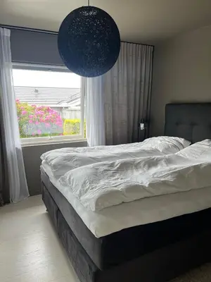 a bedroom with a bed and a window with flowers at Modern detached house by the mountains & sea in Eidsvåg